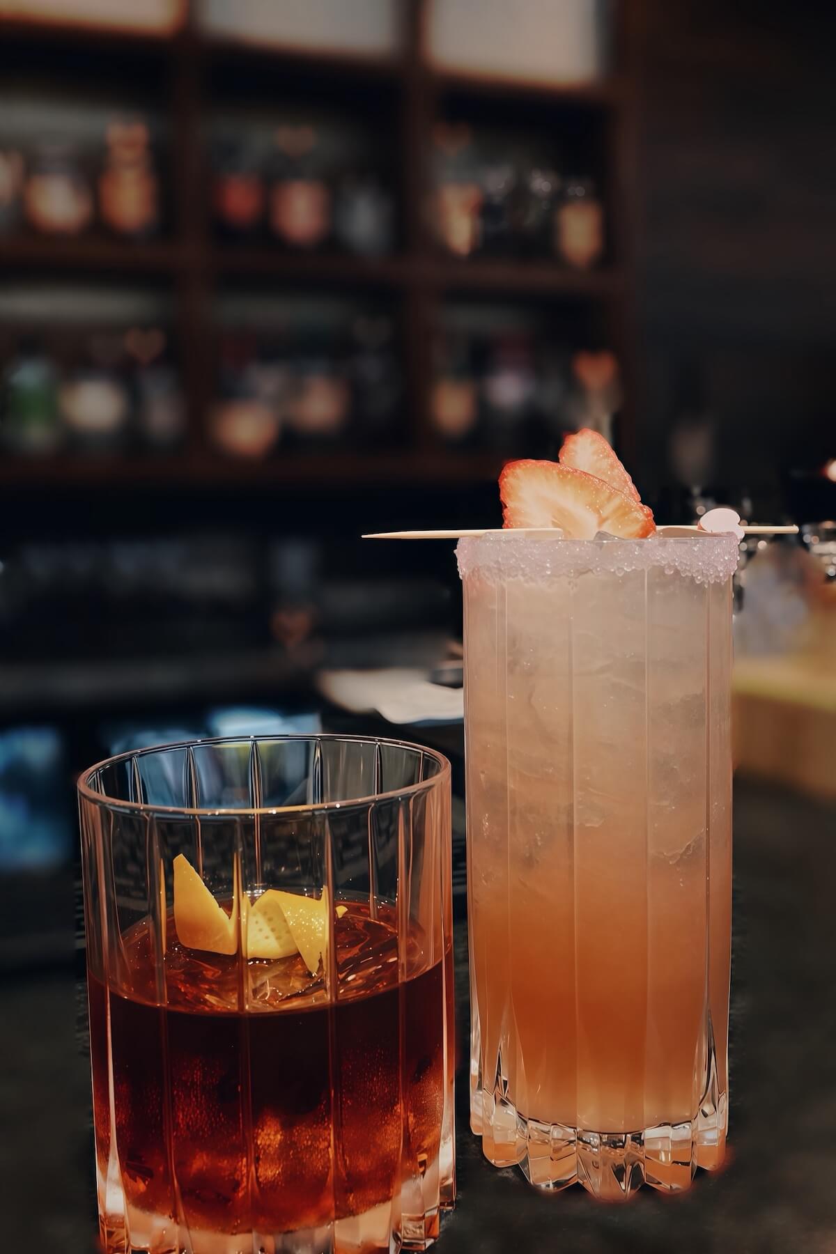 An old fashioned and a sugar-rimmed highball garnished with dried strawberry