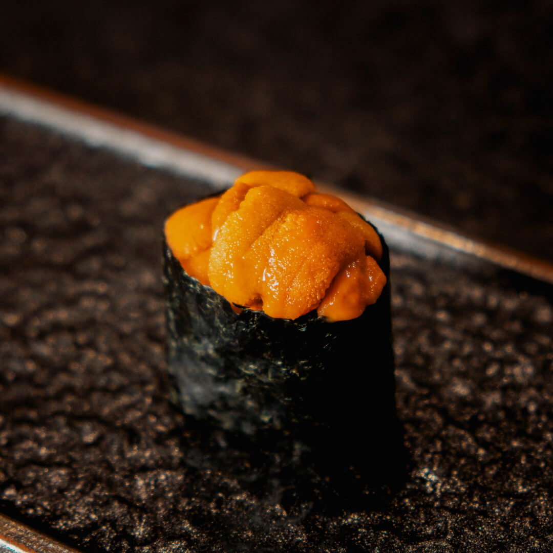 Sea urchin nigiri wrapped in nori on a ceramic plate