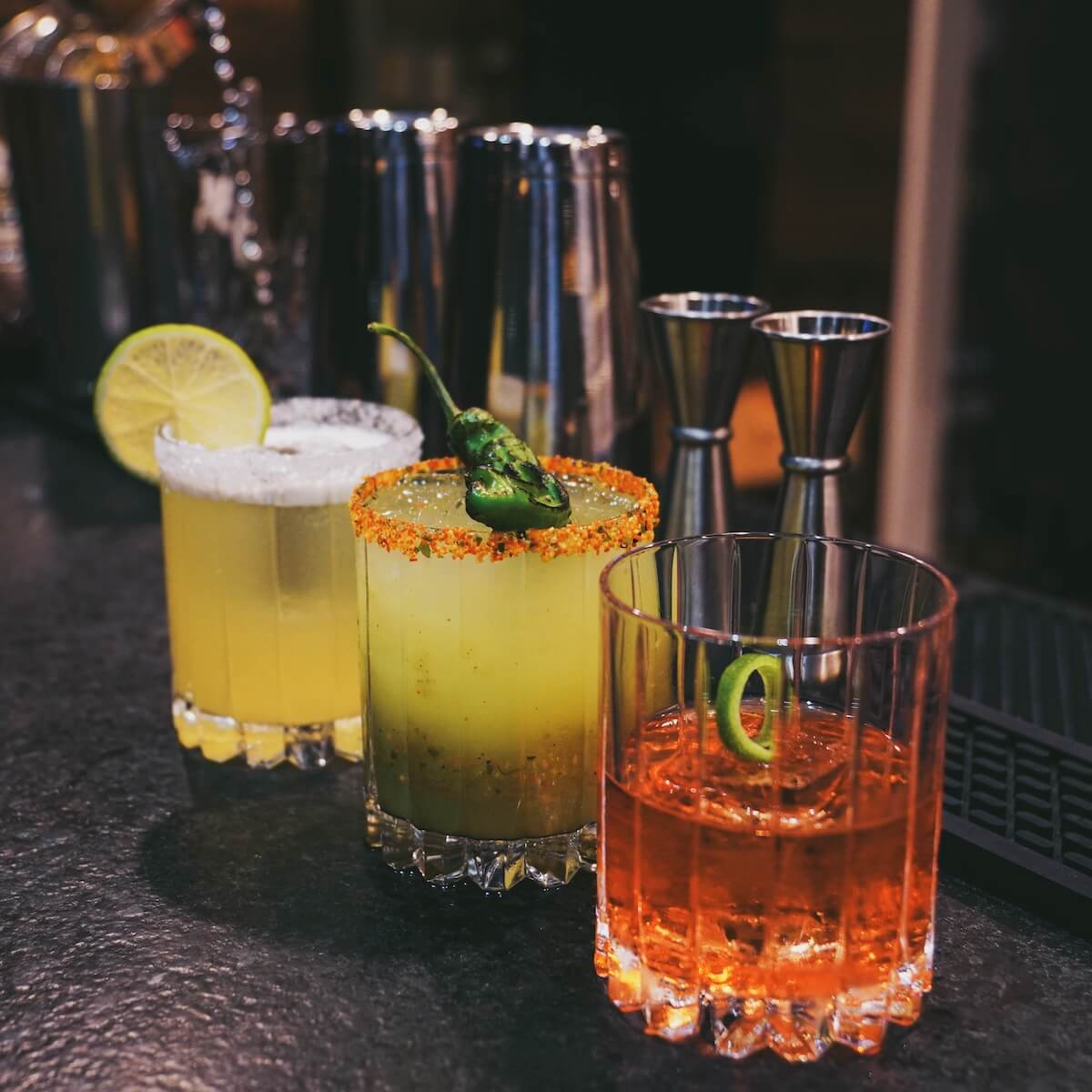 Craft cocktails — margaritas with salt and chili-lime rims and a charred serrano