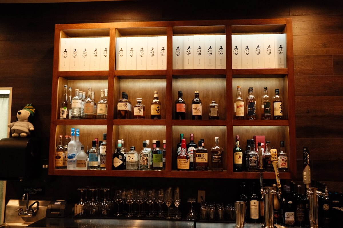 Back bar shelves of Japanese whisky beneath boxed Kubota sake