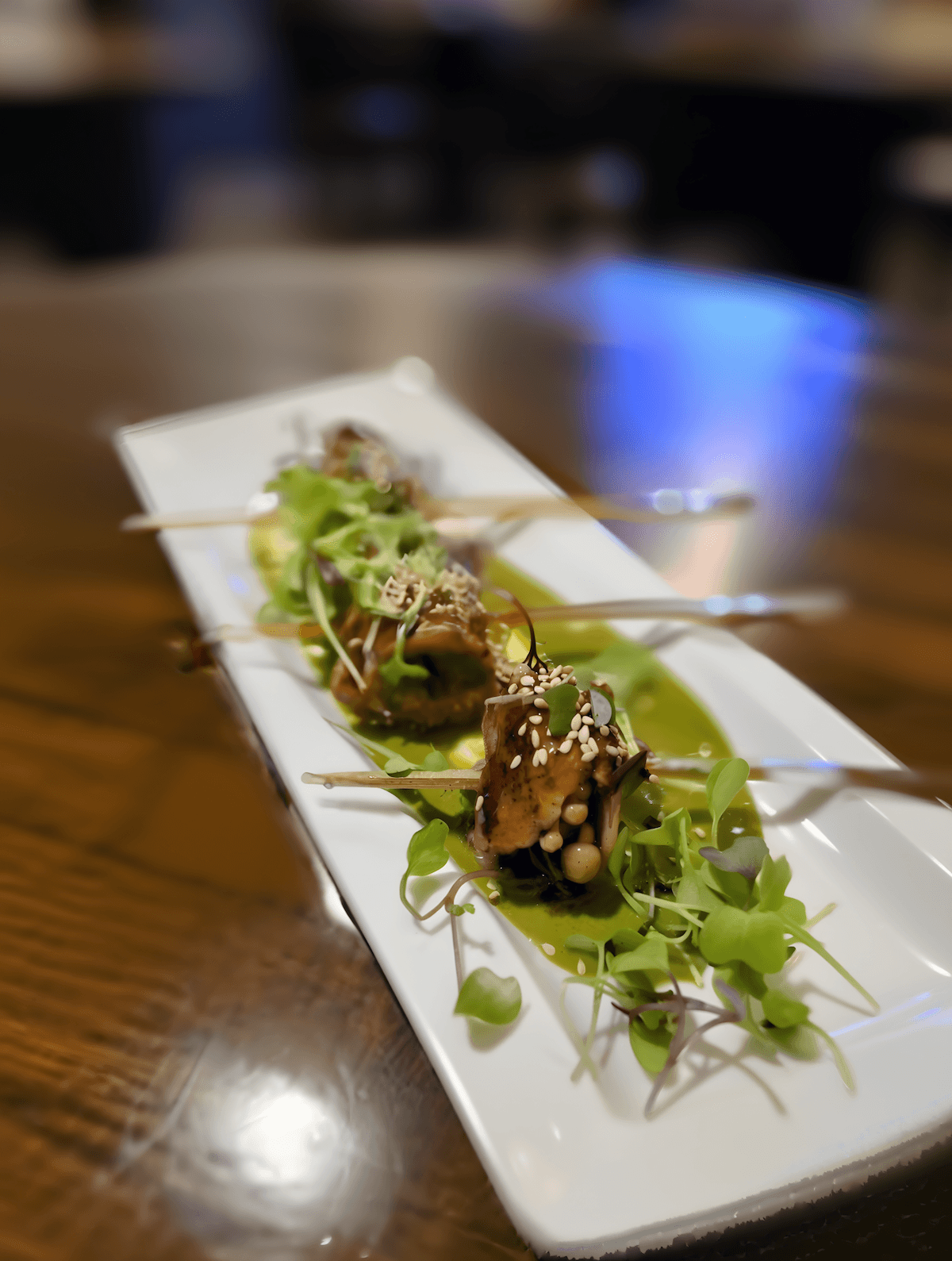 Grilled skewers glazed and finished with sesame and micro greens over herb oil