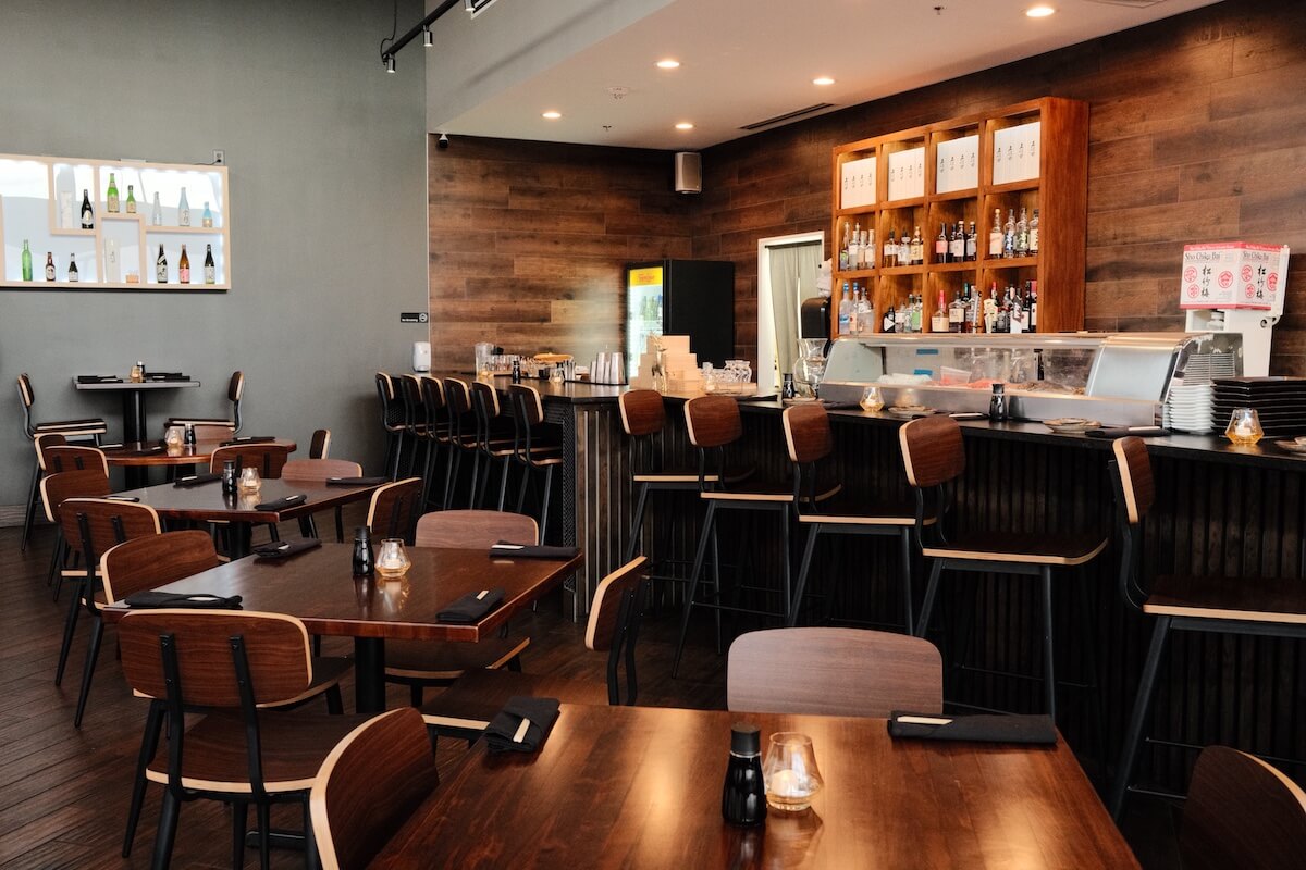 Dining room tables beside the sushi bar counter and sake display