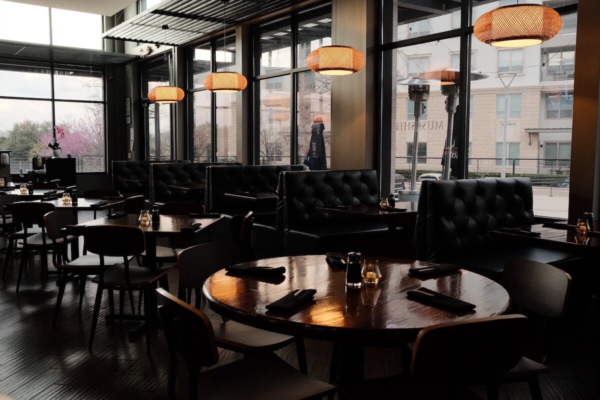 Round dining table and leather banquettes under woven pendant lights