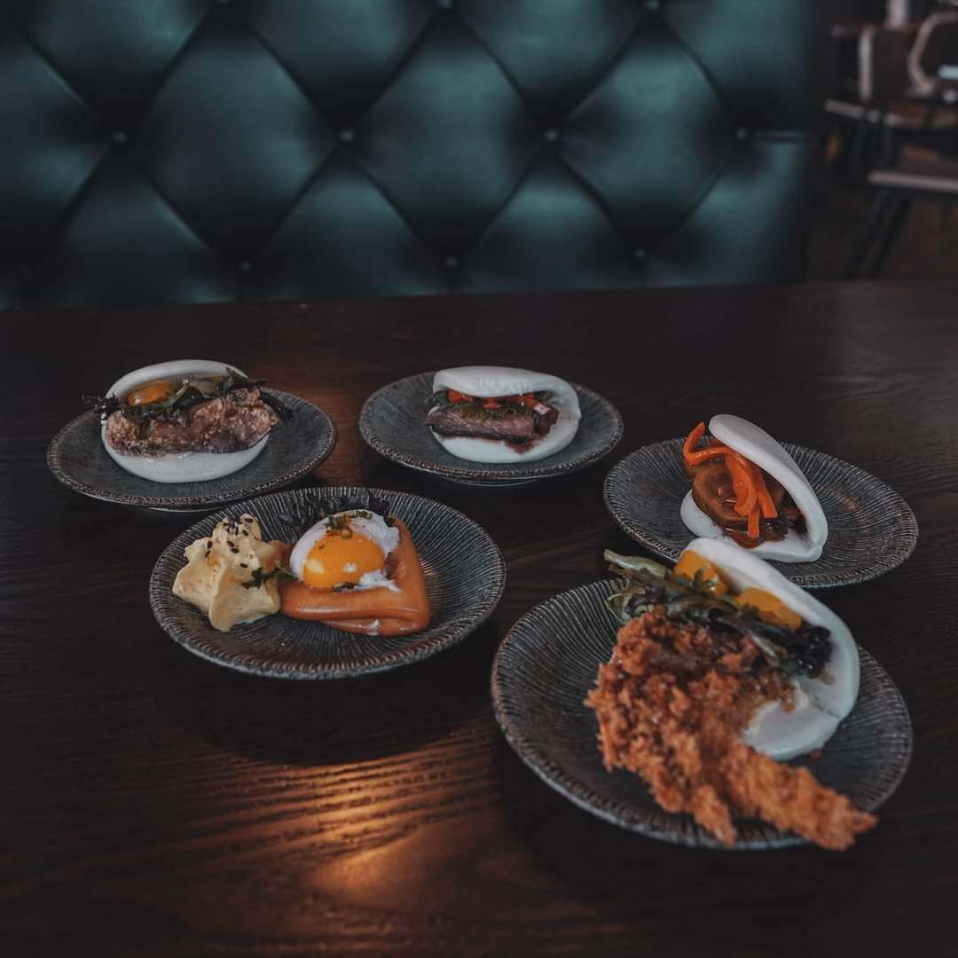 Assorted bao buns and izakaya small plates on ceramic dishes