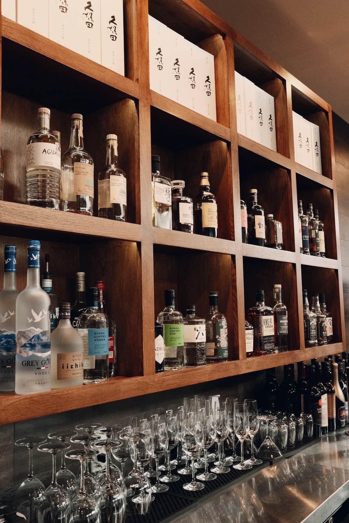 Back bar shelves of Japanese whisky, shochu and boxed Kubota sake above rows of glassware