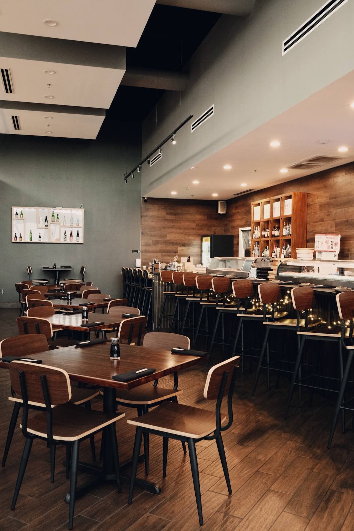 Dining room tables with the sushi counter and bar stools behind