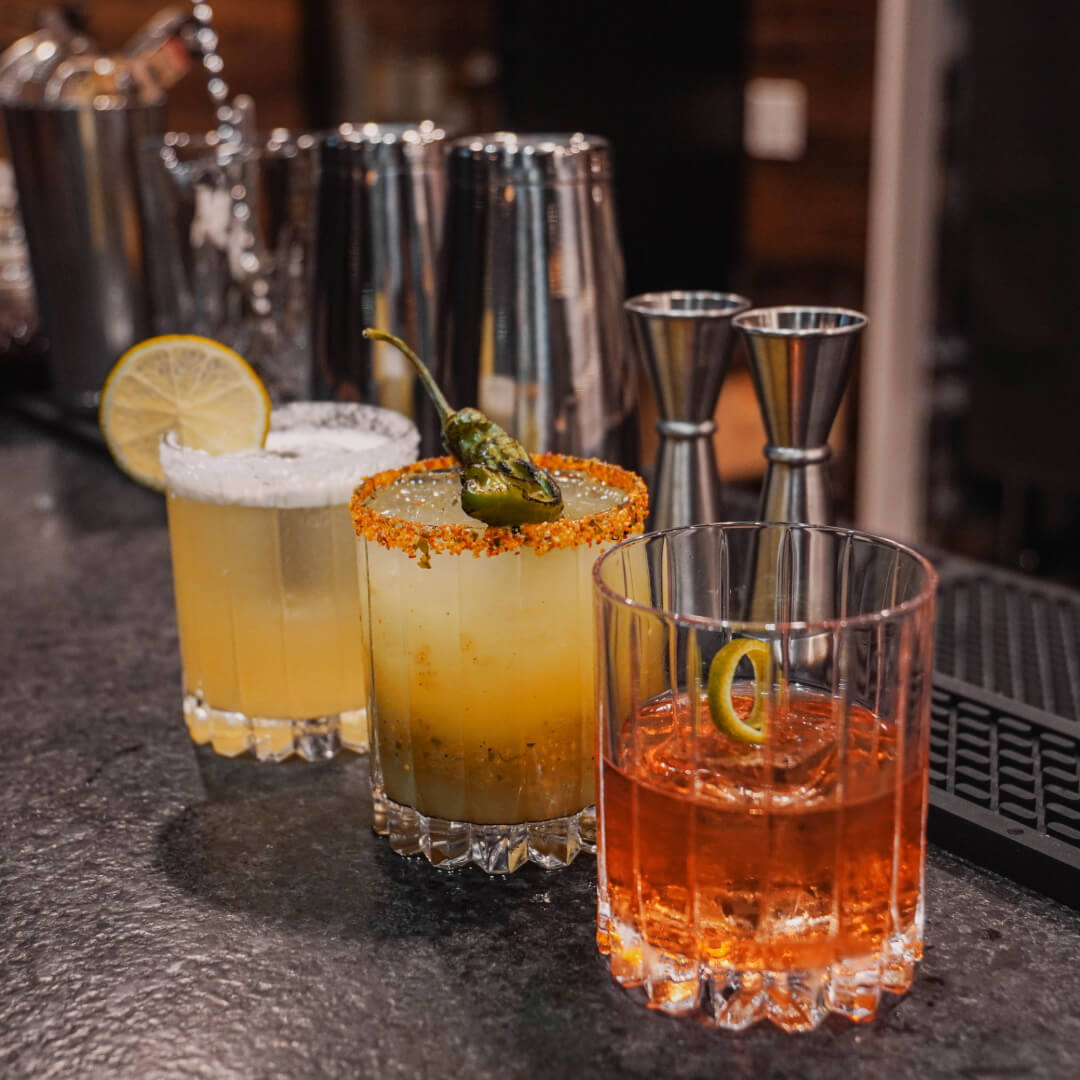 Margaritas with salt and chili-lime rims, garnished with lime and a charred serrano