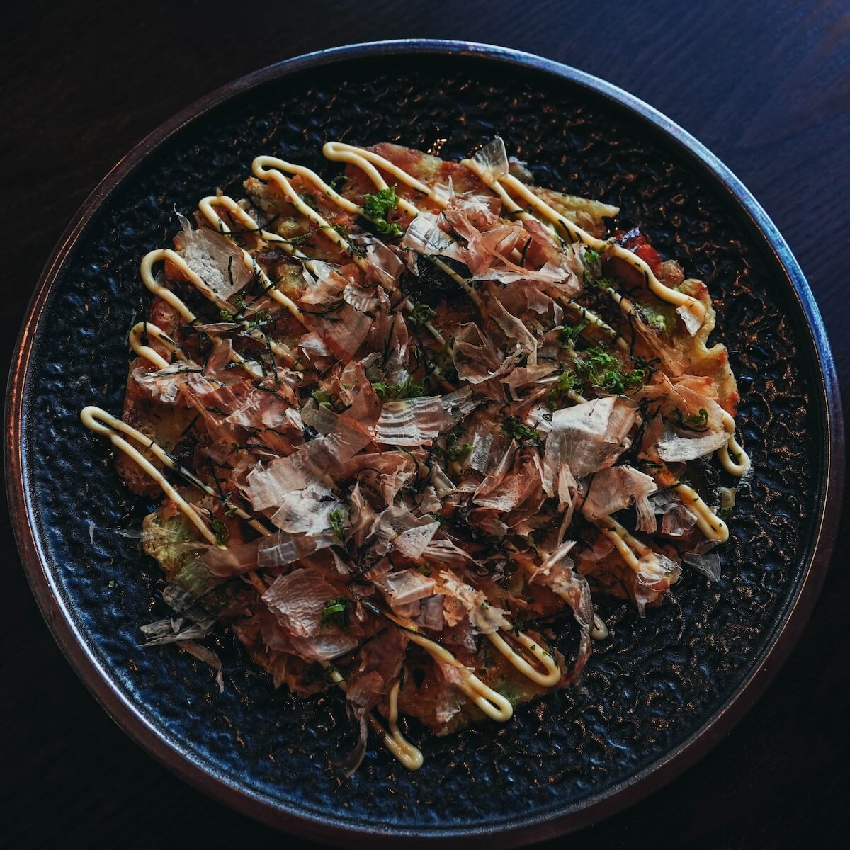 Okonomiyaki topped with bonito flakes, aonori and Japanese mayonnaise