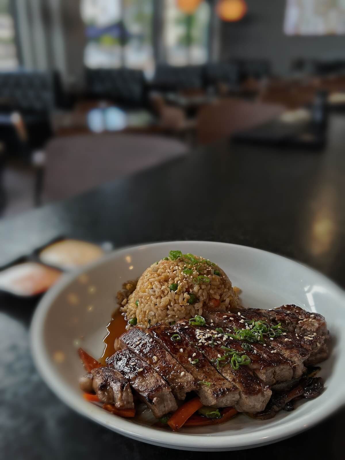 Japanese ribeye teppanyaki, sliced over fried rice with vegetables and sesame