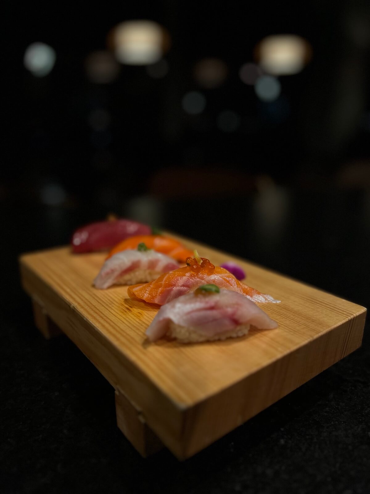 Nigiri tasting on a wooden board — tuna, salmon and yellowtail