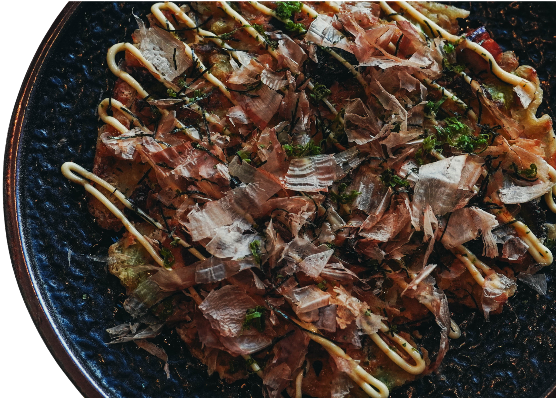 Okonomiyaki topped with bonito flakes, aonori and Japanese mayonnaise