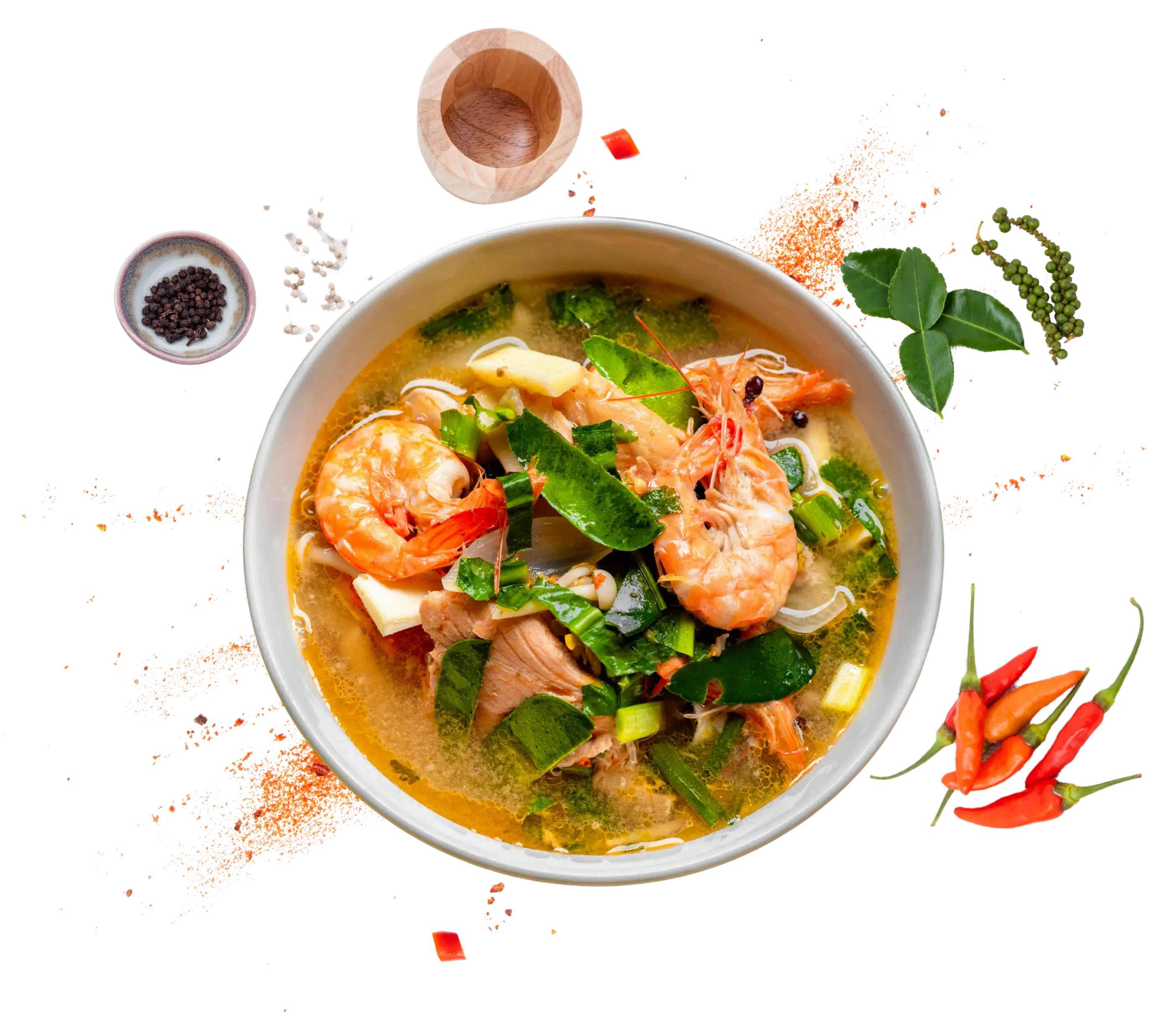 Tom yum soup with shrimp, surrounded by fresh Thai chilis, lime leaves and spices
